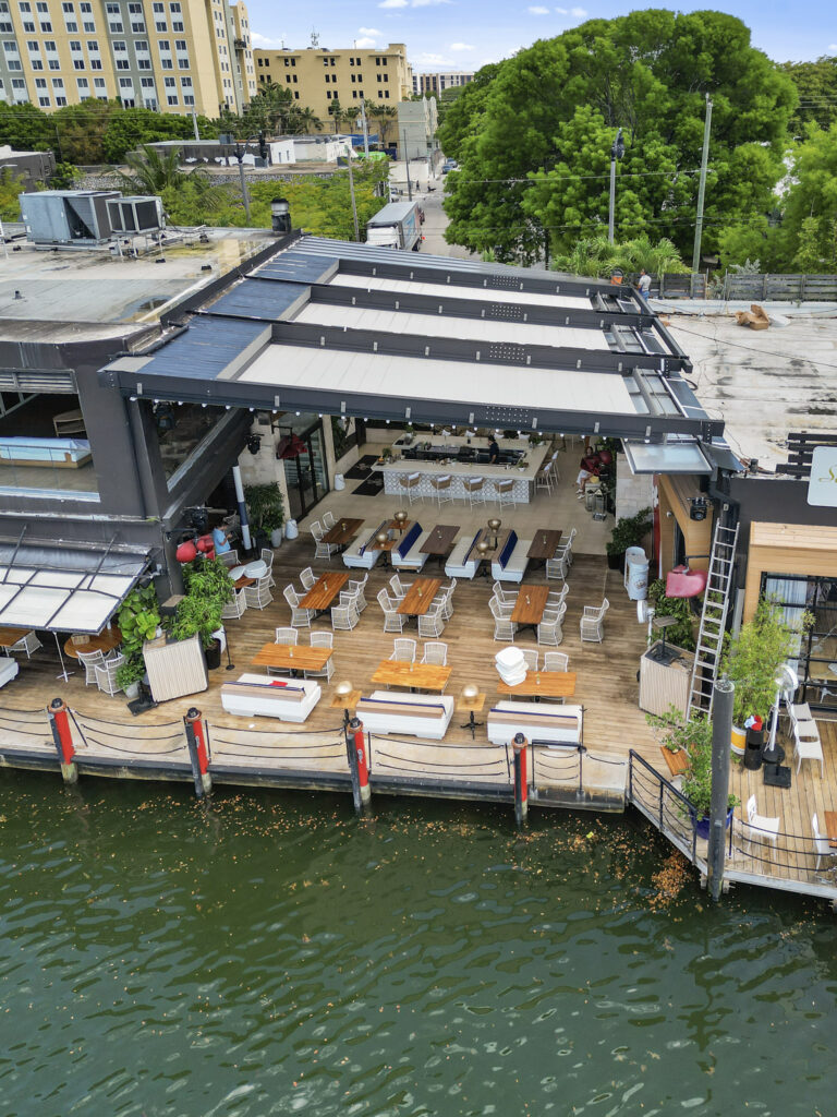 RETRACTABLE AWNING OVER OUTDOOR WATERFRONT DINING SPACE